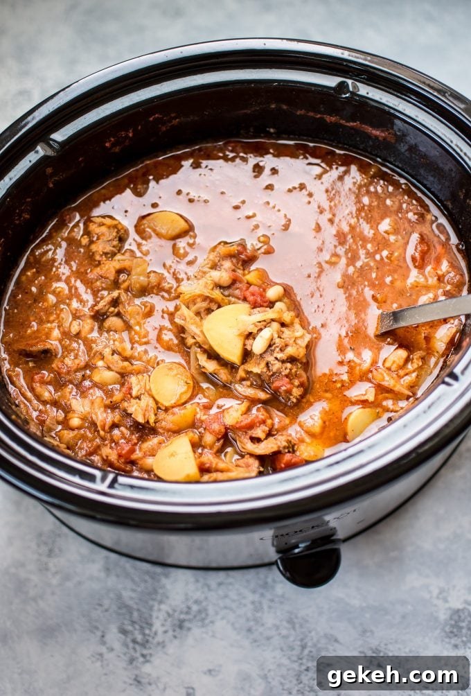 Hearty Crockpot Cabbage Soup with Sausage, Beans & Potatoes 3 cabbage soup with sausage in a slow cooker with ladle