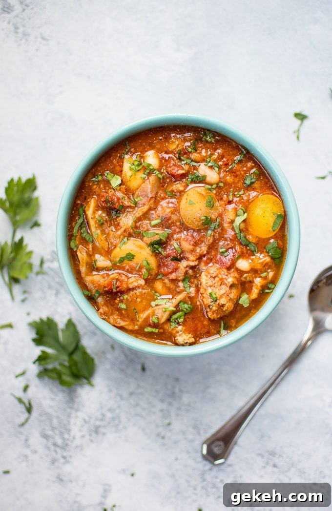 Hearty Crockpot Cabbage Soup with Sausage, Beans & Potatoes 4 bowl of Crockpot cabbage soup beside parsley sprigs and a spoon