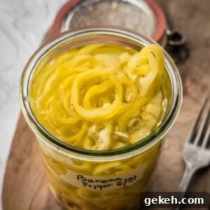 An open jar of pickled banana peppers on a wooden board.
