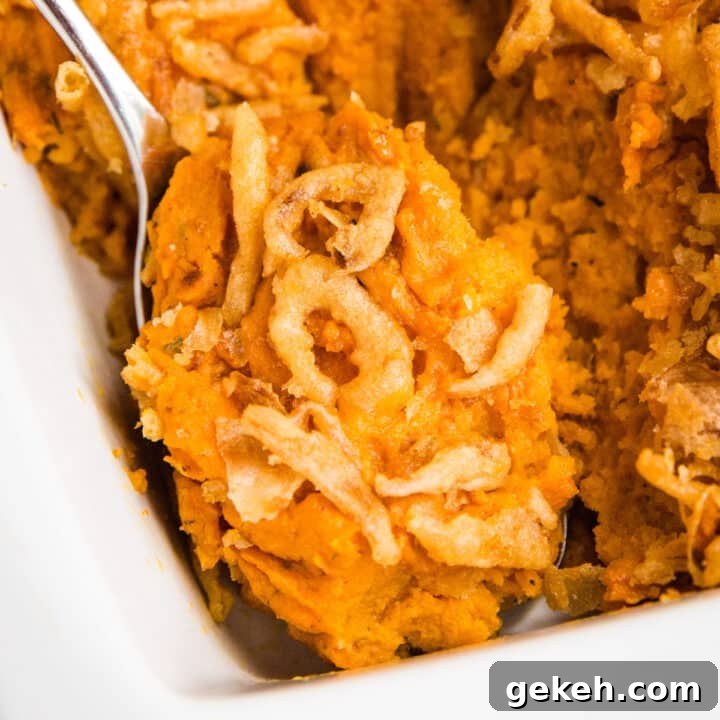 A close up of a serving spoon in a pan of savory sweet potato casserole.