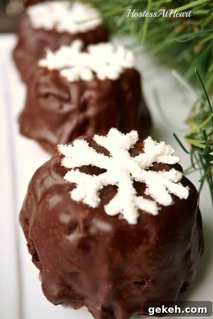Small cake bundtlettes frosted with chocolate ganache and topped with a sugar snowflake.