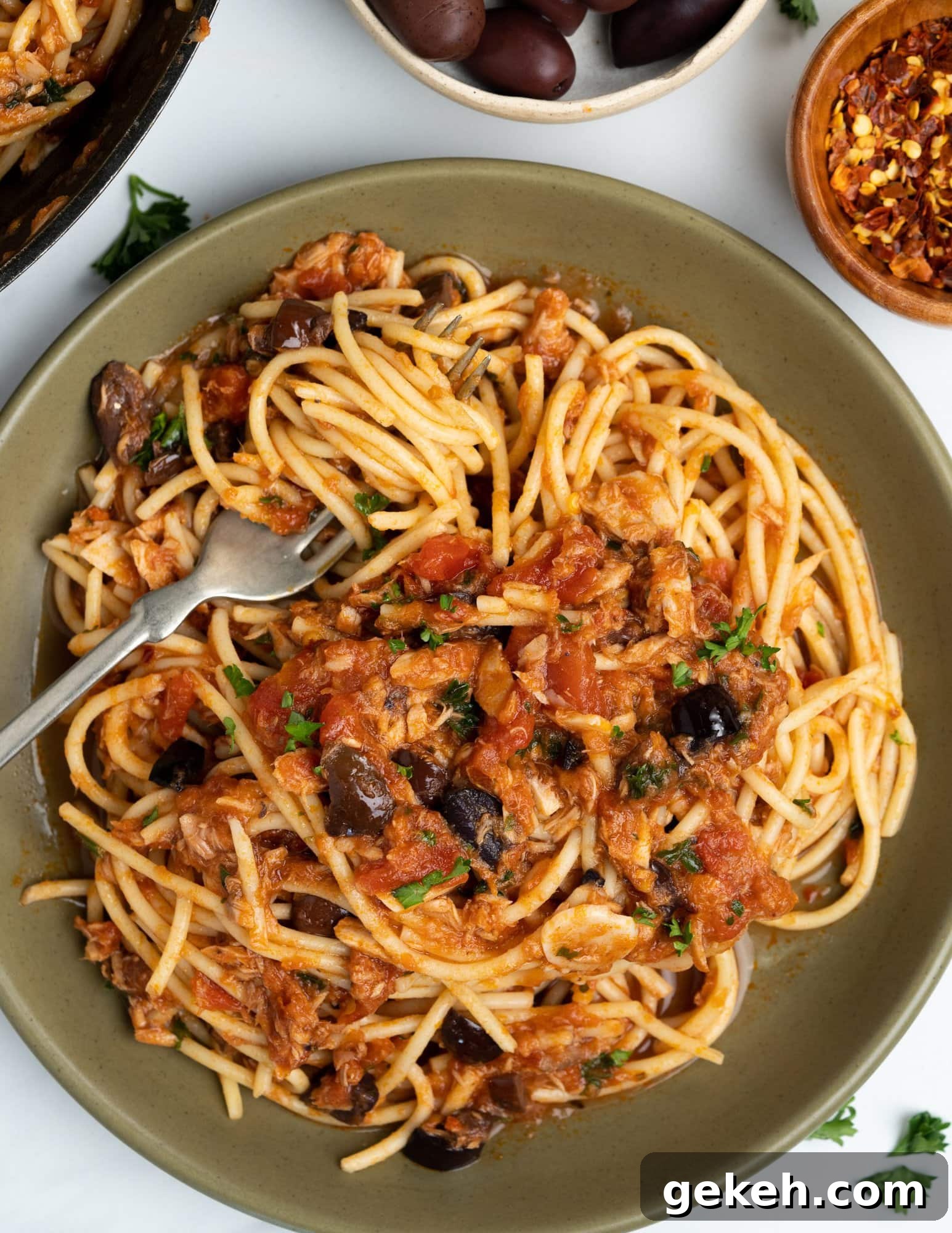 Quick Canned Tuna Pasta Recipe for Weeknight Dinners 7 Tomato tuna pasta with Spaghetti, tomato and tuna sauce with olives and seasonings, garnished with parsley.
