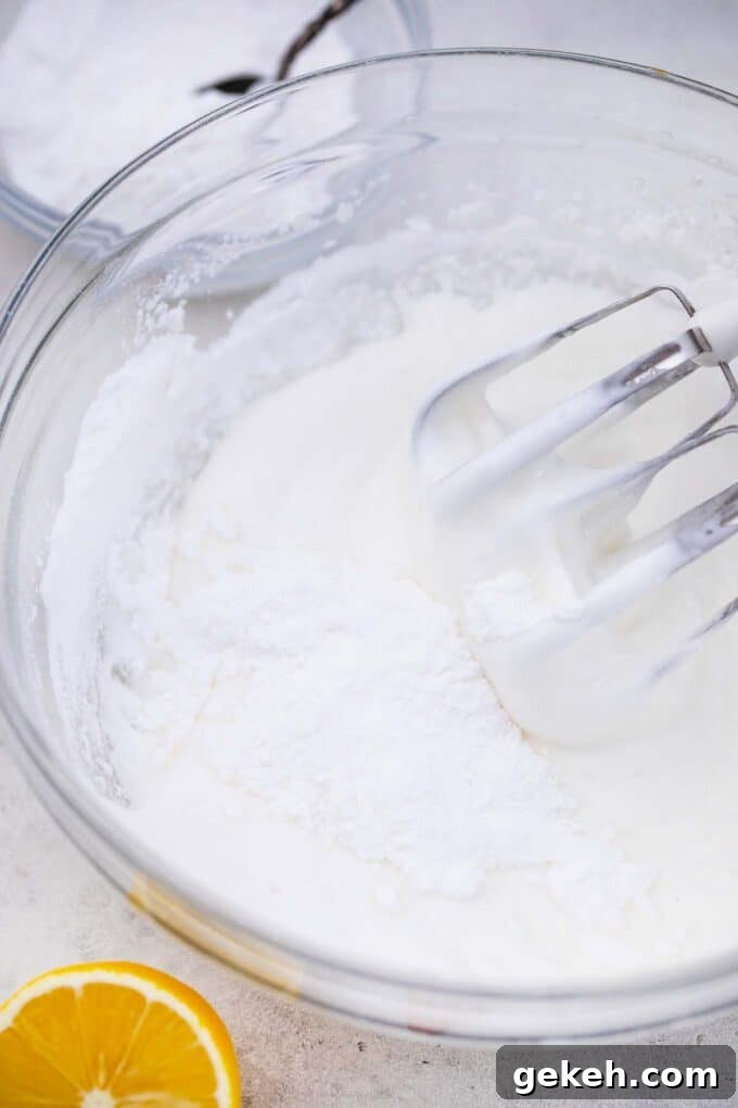 How to Make Smooth Royal Icing for Perfect Cookies and Cakes 6 a bowl of fluffy egg white with a mixer in it