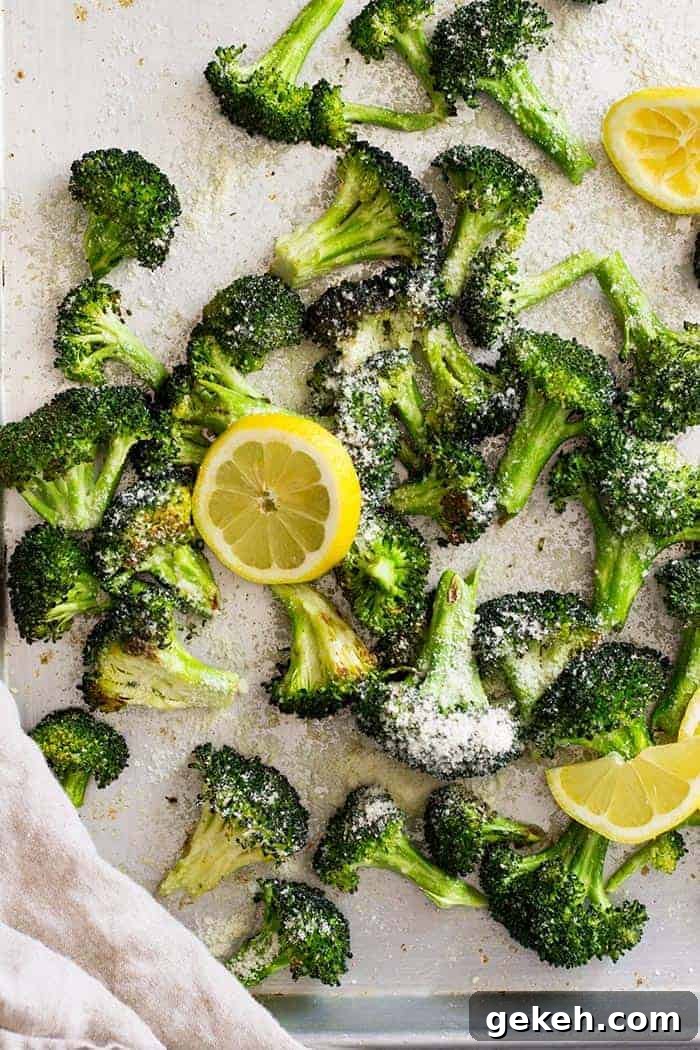 Lemon Parmesan Roasted Broccoli Recipe 3 Top down view of lemon parmesan roasted broccoli on a sheet pan with lemon slices.