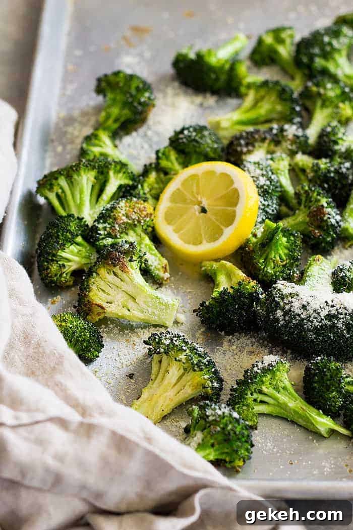 Lemon Parmesan Roasted Broccoli Recipe 4 Lemon parmesan roasted broccoli on a sheet pan with a slice of lemon.