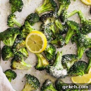 Lemon Parmesan Roasted Broccoli Recipe 5 Top down view of lemon parmesan roasted broccoli on a sheet pan with lemon slices.