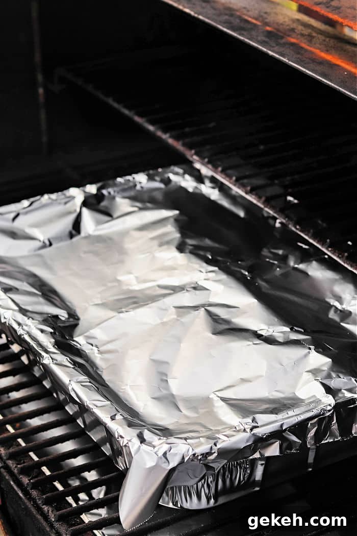 Smoked Chuck Roast Recipe: Tender, Juicy BBQ Roast 5 A foil-covered baking pan with smoked chuck roast sits on the rack inside a grill or oven.