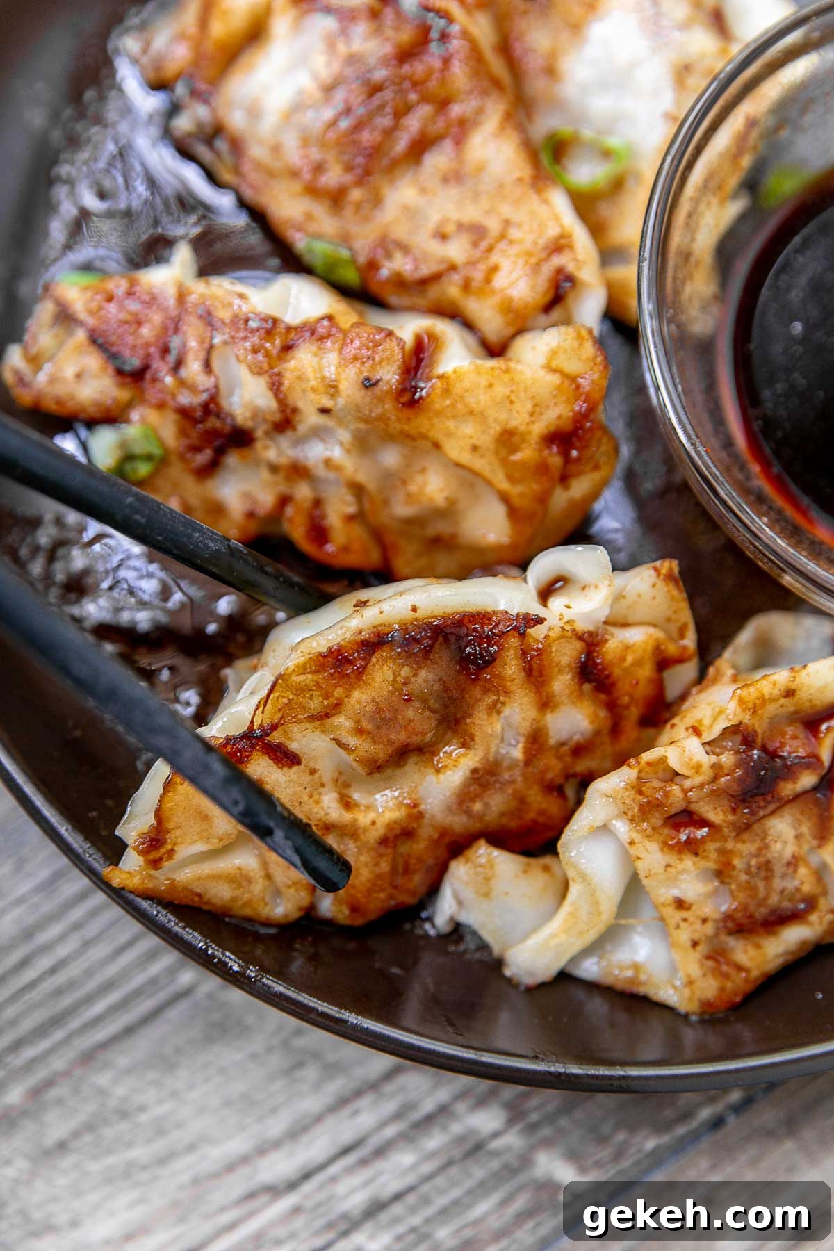 Crispy Pork Potstickers: Homemade Dumplings with Savory Filling 2 Pork potstickers with dipping sauce on a serving platter.