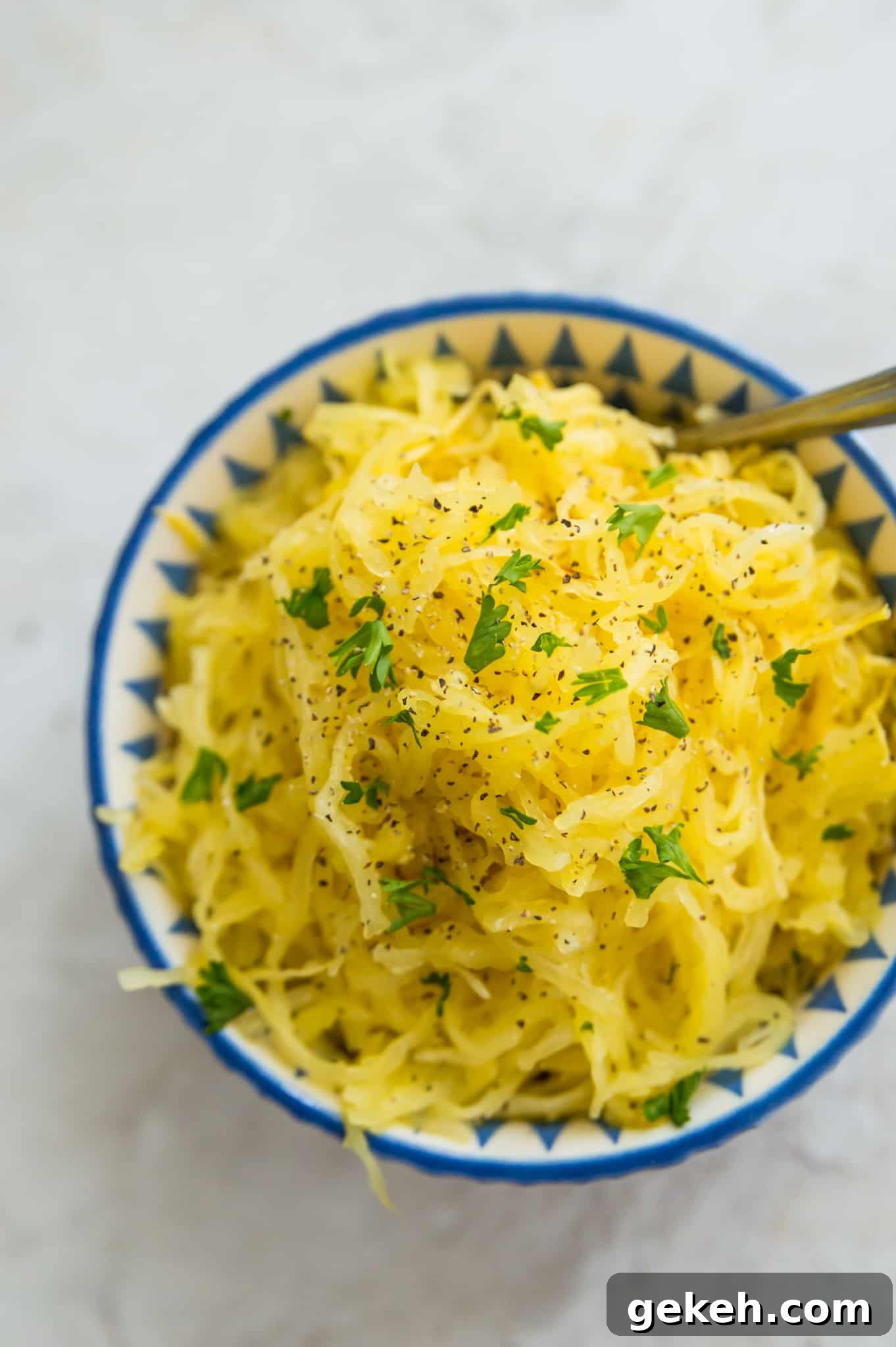 A bowl of cooked spaghetti squash with fresh parsley on top.