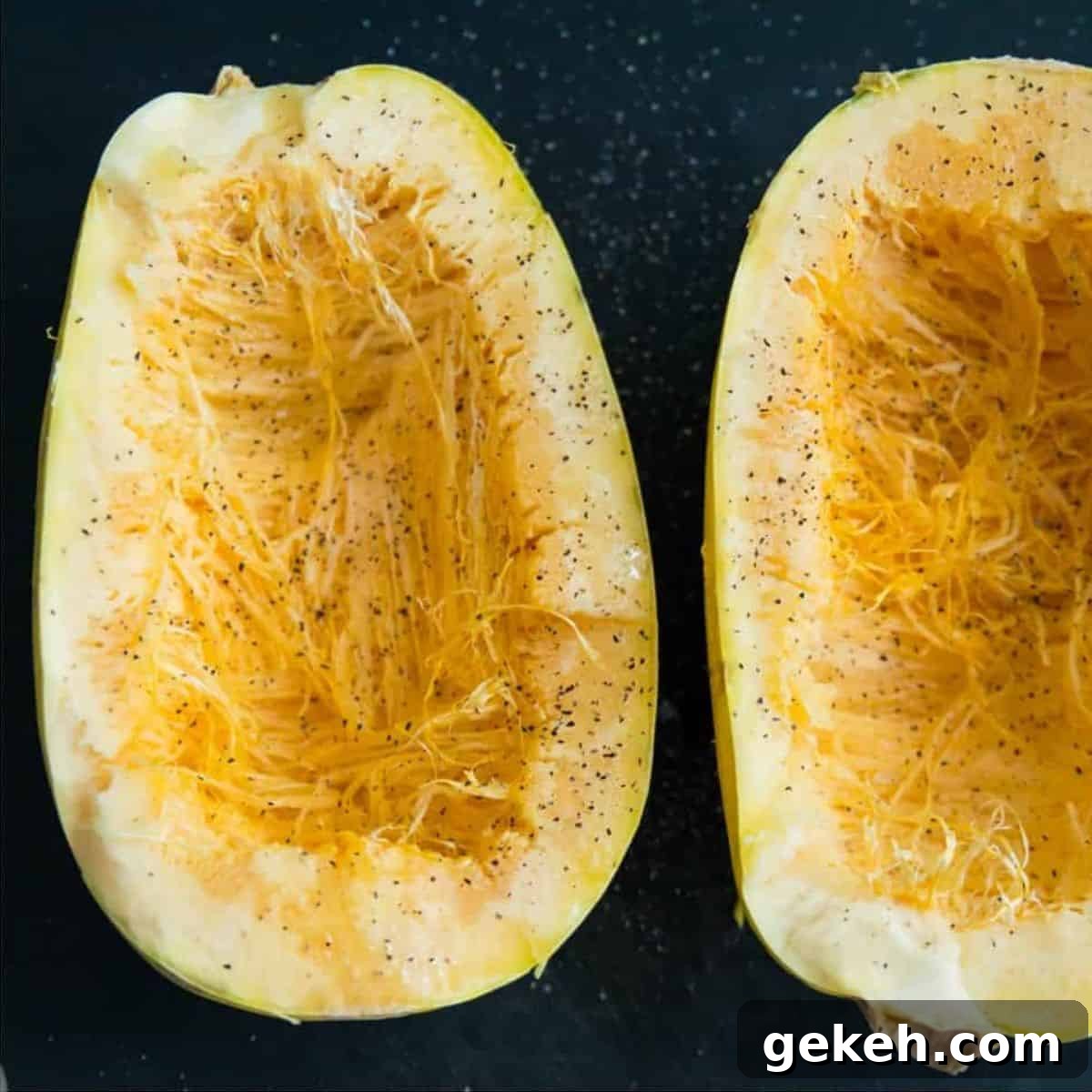 A spaghetti squash that is cut in half and coated in salt and pepper.