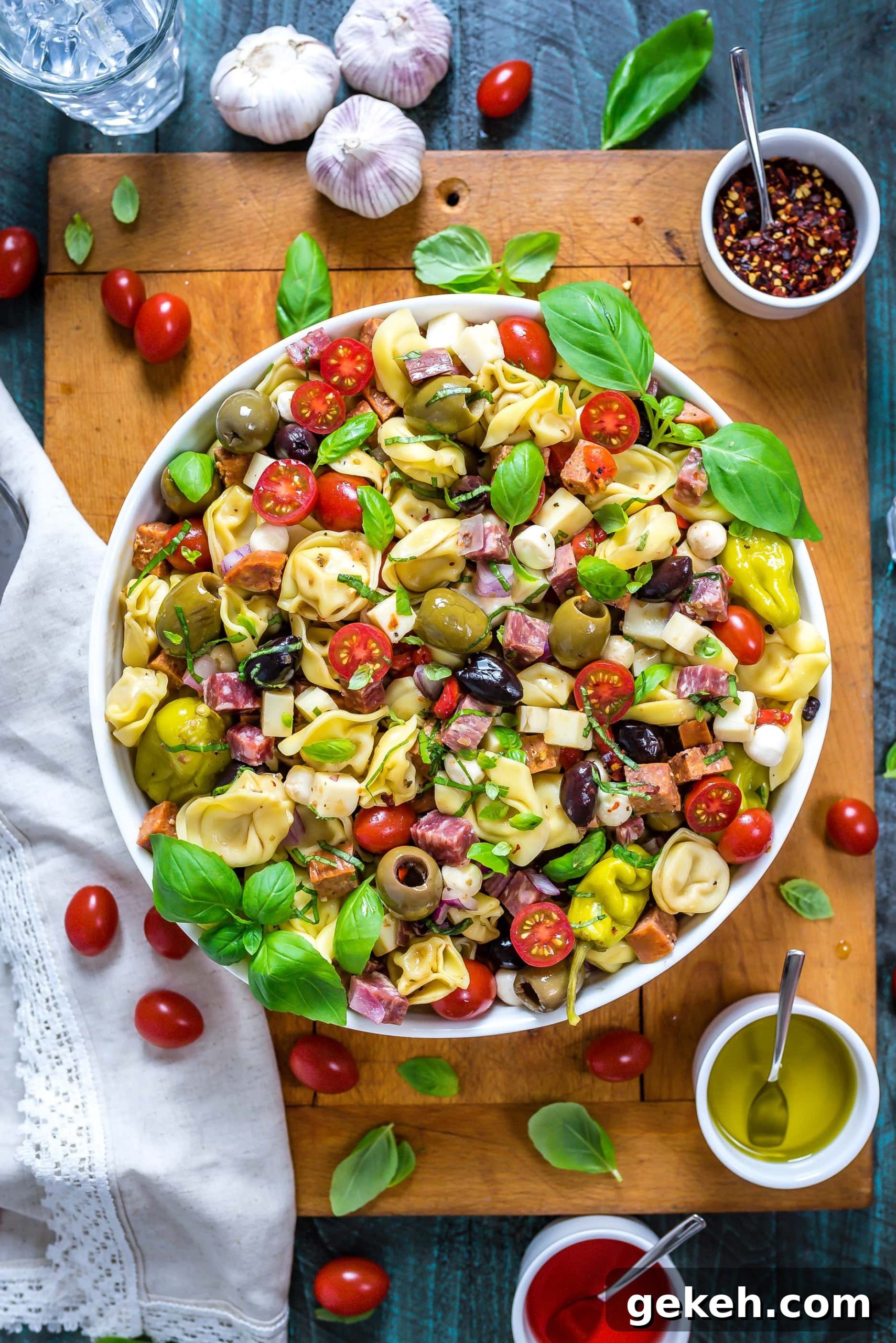 Antipasto Tortellini Pasta Salad in a large white bowl that rests on top of a wooden cutting board.