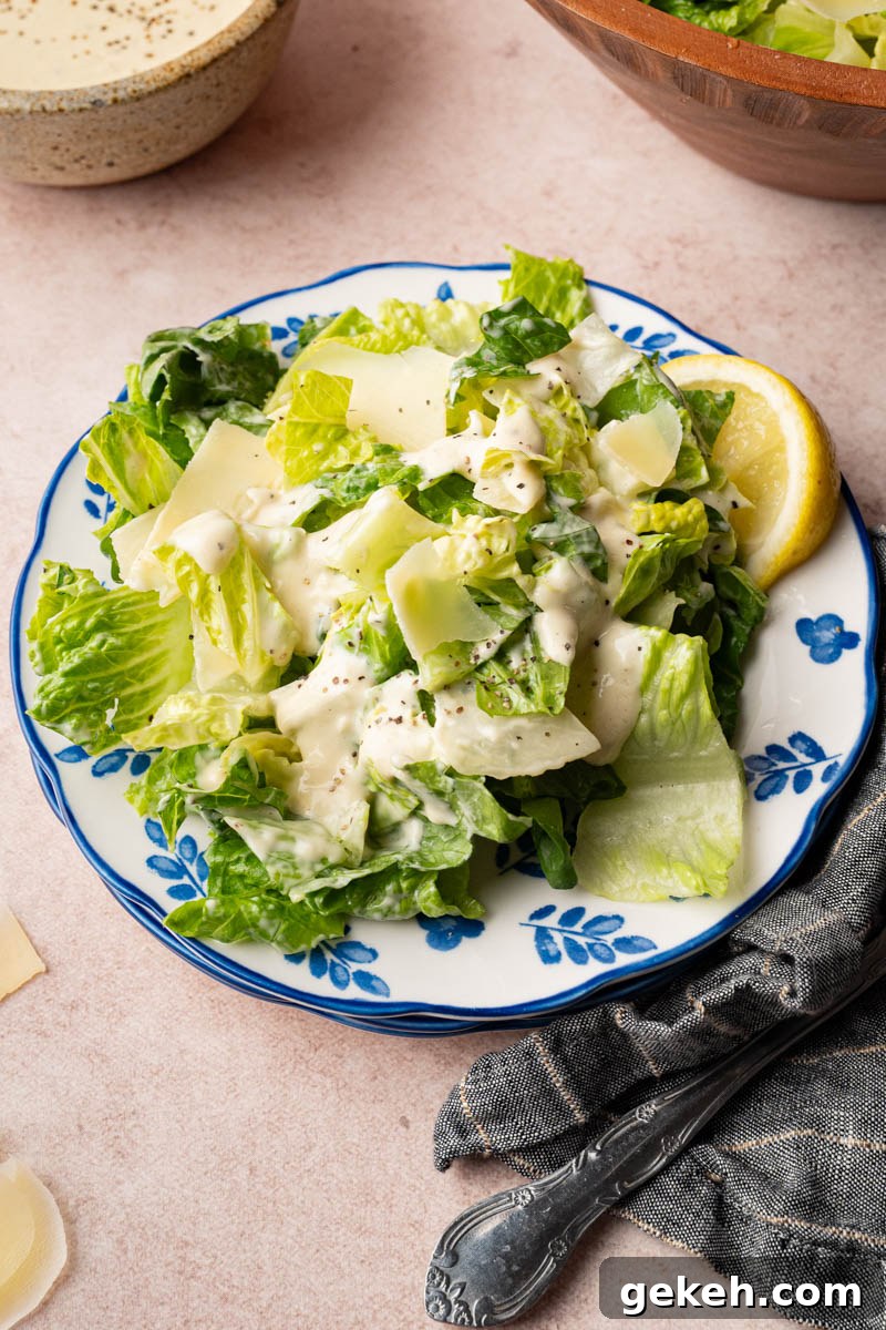 Caesar salad on a plate with a lemon wedge for serving.