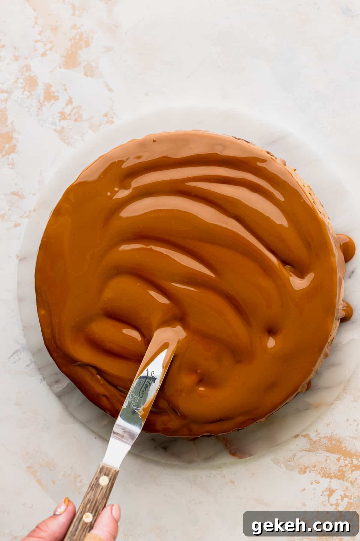 Spreading cookie butter on top of cheesecake.