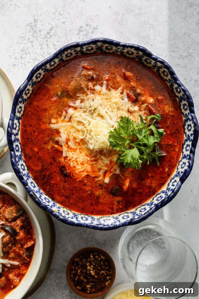 a large blue bowl of gluten free instant pot pizza soup next to two white bowls of soup.