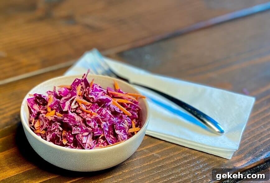 Classic Homemade Coleslaw Recipe with Creamy Tangy Dressing 4 Served in a small bowl with a fork and napkin.