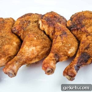 Four Smoked Chicken Leg Quarters are arranged in a row on a white plate.