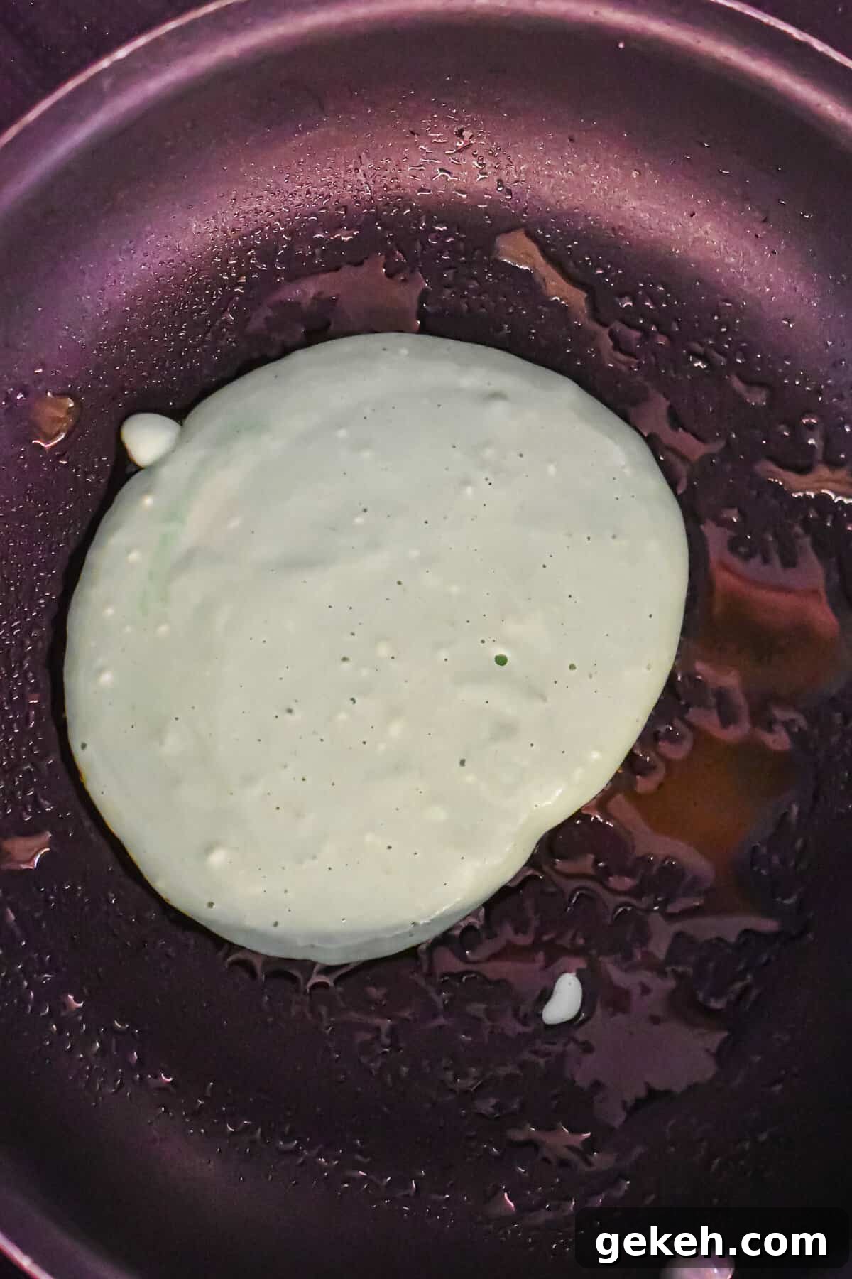 Homemade Grinch Pancakes Recipe — Green St. Patrick’s Breakfast 8 A scoop of pancake batter is in a pan.
