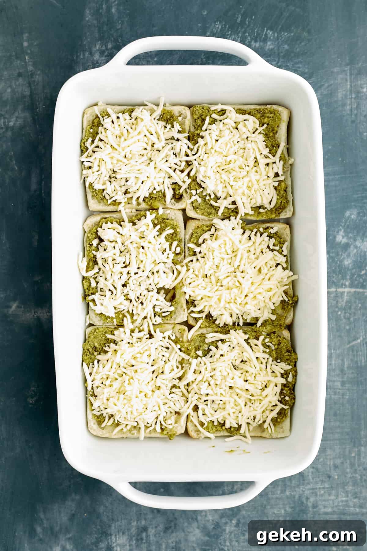 Turkey Caprese Sandwich with Fresh Mozzarella & Basil 5 sliced bread in a baking dish topped with pesto and cheese.