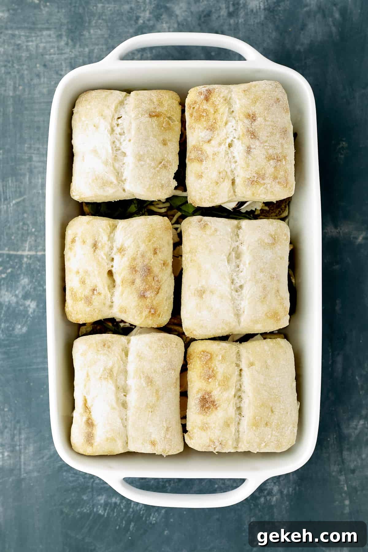 Turkey Caprese Sandwich with Fresh Mozzarella & Basil 10 turkey caprese sandwiches in a white baking dish ready to be baked.