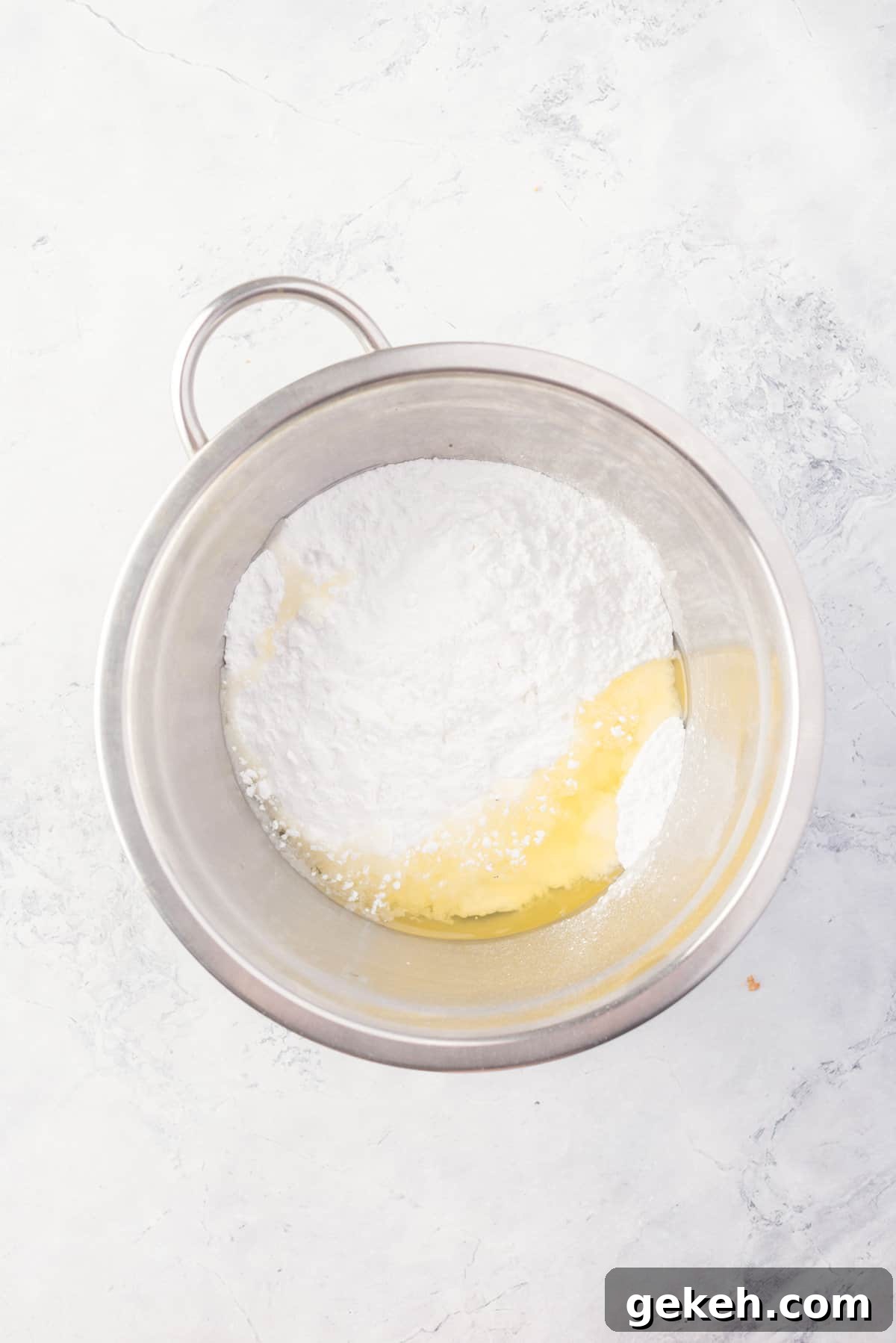 Overhead view of icing ingredients before mixing in mixing bowl.