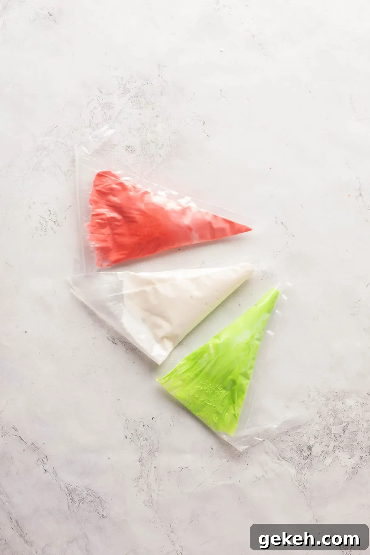 Overhead view showing three bags of icing mixture in red, white and green colors.