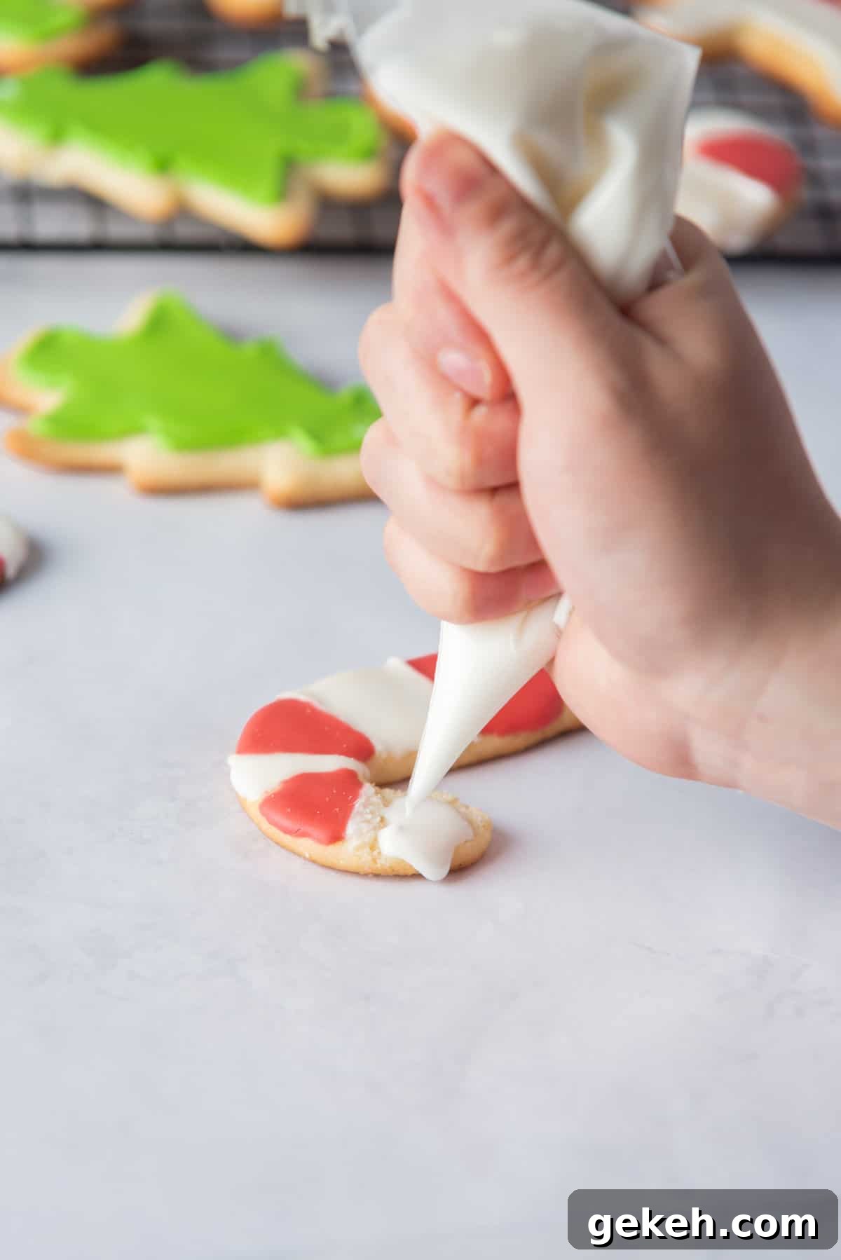 Overhead view of hand piping icing onto cookies.