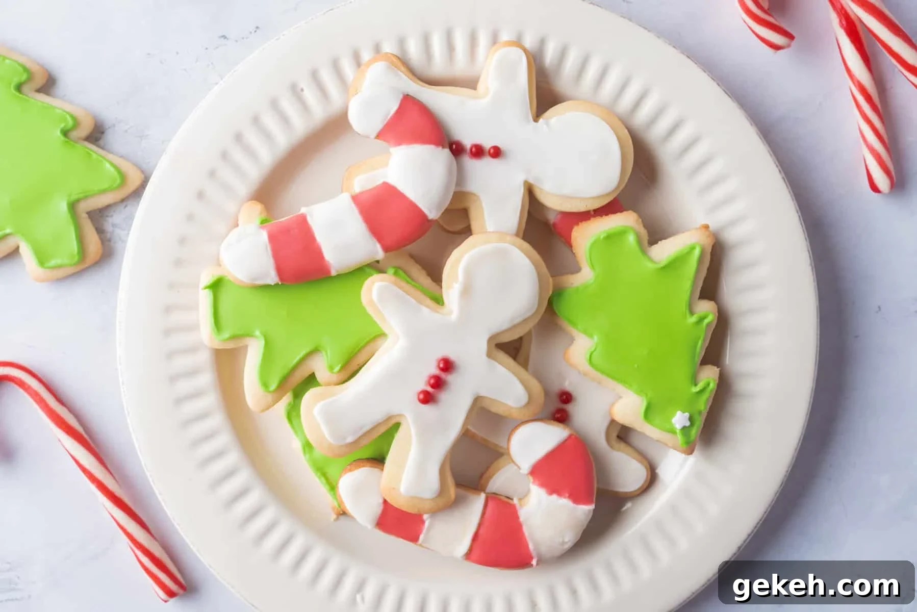 Overhead view of Christmas sugar cookies on a white plate, with cookies on the side as well.