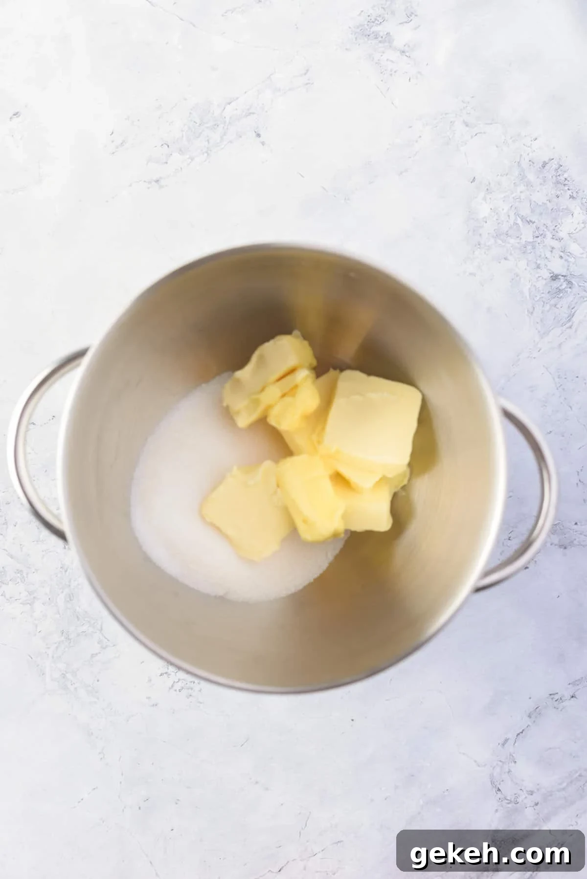 Overhead view of butter and sugar in a large mixing bowl. 