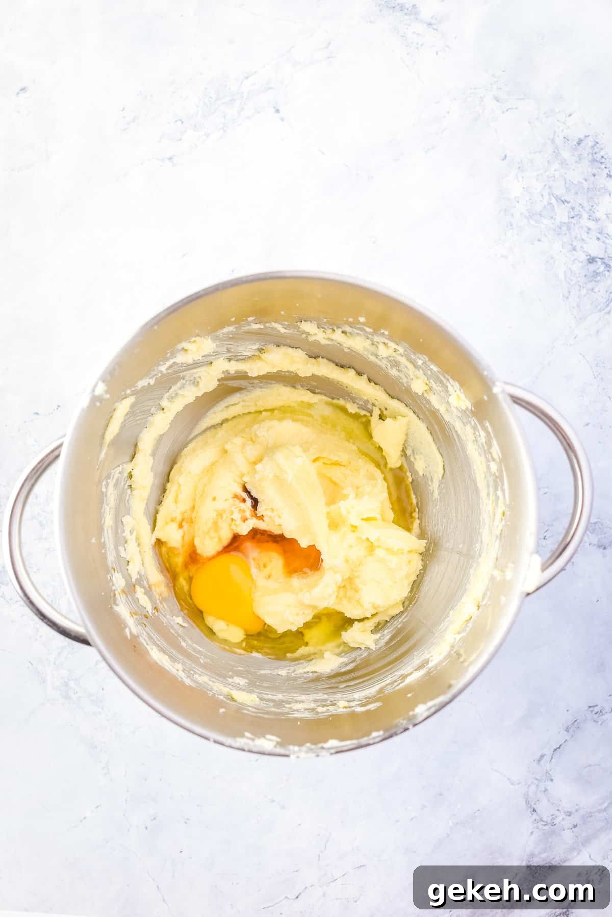 Overhead view of egg and vanilla added to creamed butter-sugar mixture.