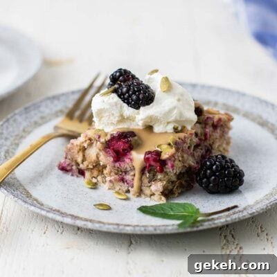 A slice of blackberry baked oatmeal on a white plate with a gold fork.