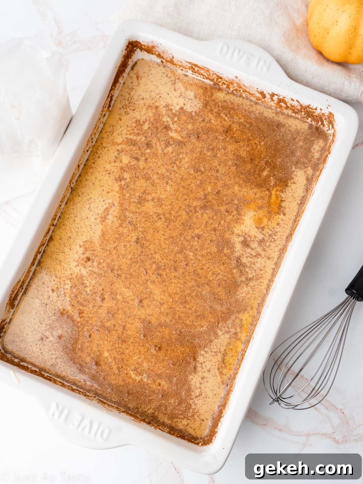 Pumpkin pie cake process shot showing wet ingredients in a cake pan.