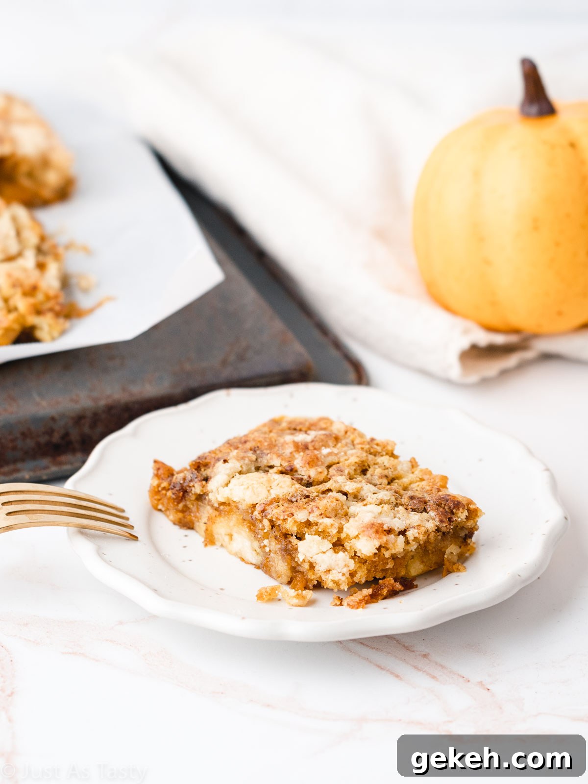 Slice of pumpkin pie cake with cake mix on a white plate with a pumpkin in the background.