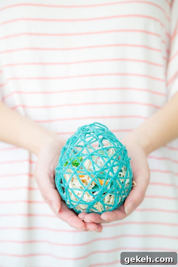 Girl holding an Easter egg made from yarn with treats inside.