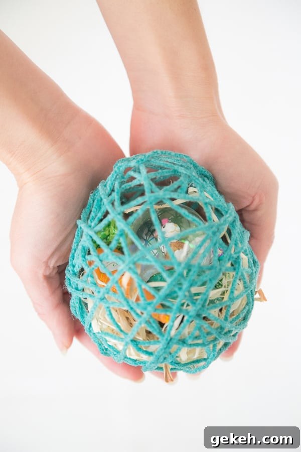 Girl holding an Easter egg made from yarn with treats inside.