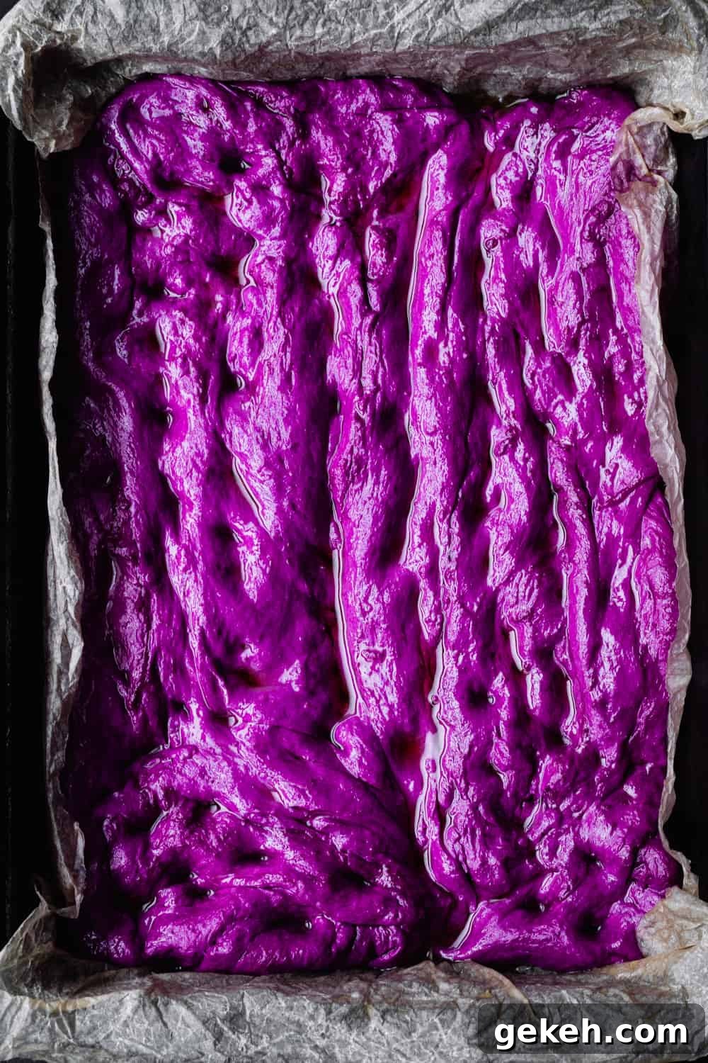 Beet Focaccia: Vibrant No-Knead Magenta Bread Recipe 5 Raw beet focaccia dough spread of a baking sheet with parchment paper; overhead shot.
