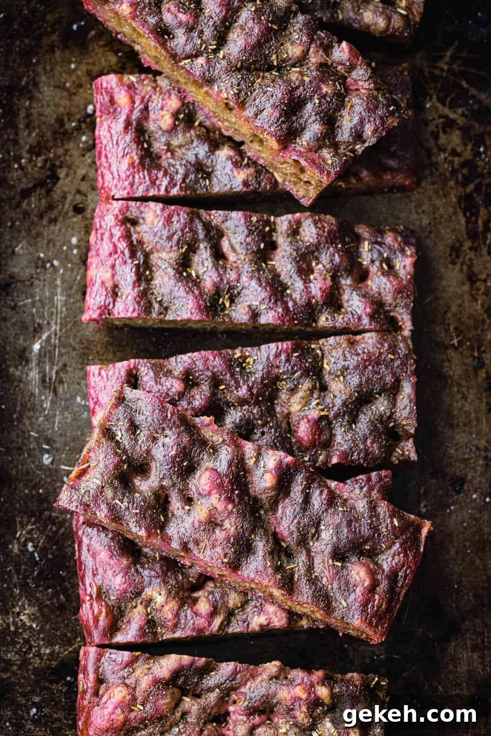 Beet Focaccia: Vibrant No-Knead Magenta Bread Recipe 9 Beet focaccia on a baking sheet and cut into slices; overhead shot.