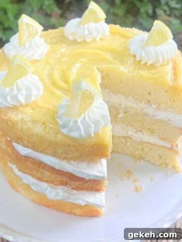 Layered Lemon Cream Cake, sliced, on a pedestal.