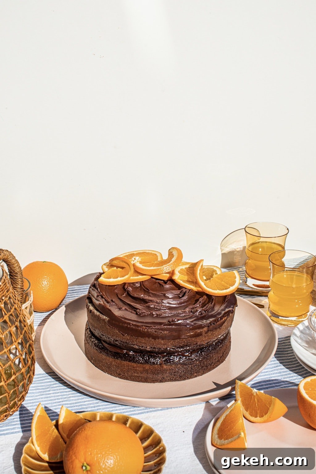 Decadent Chocolate Orange Cake Recipe 6 chocolate cake on top of a pink platter with oranges slices and chocolate ganache on top