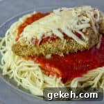A close up picture of chicken parmesan on spaghetti pasta.