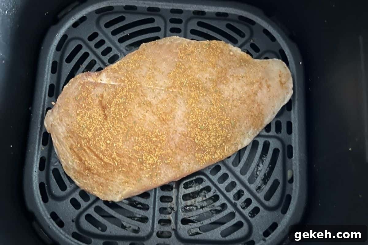 Crispy Air Fryer Chicken Breast Recipe — Juicy in 20 Minutes 5 Seasoned chicken breast in air fryer basket.