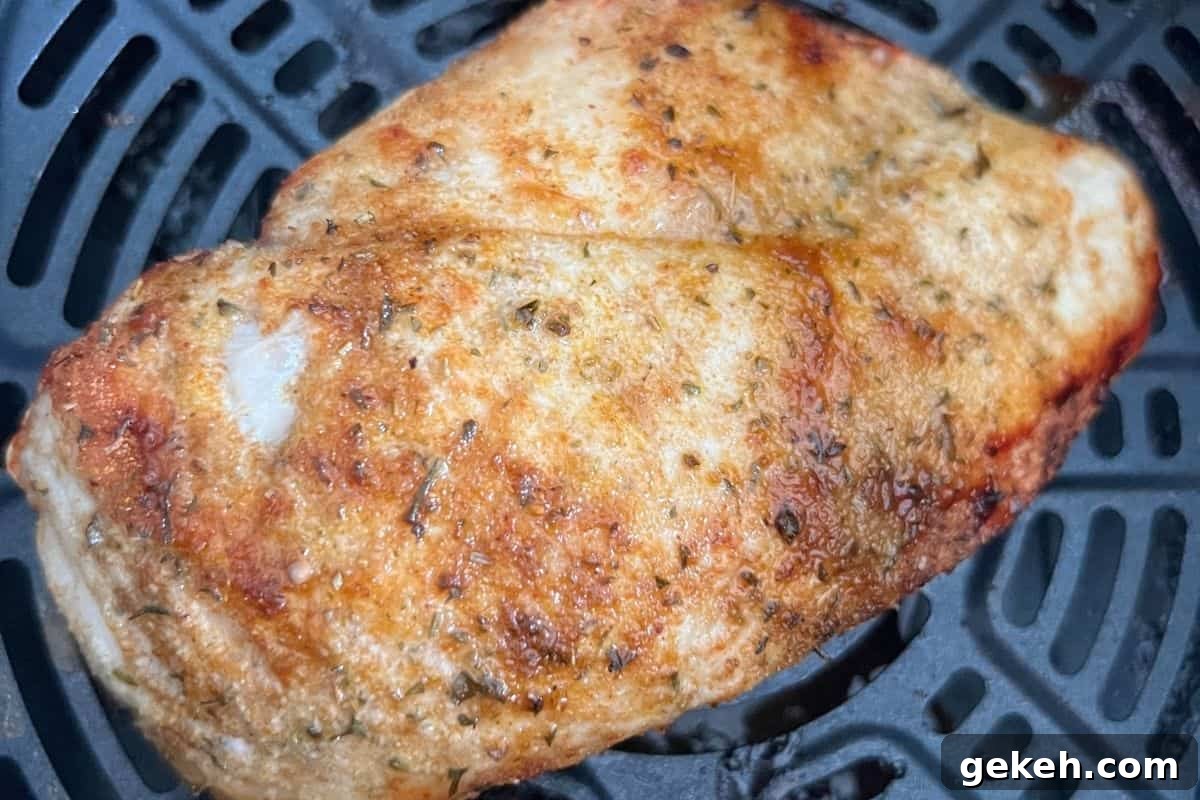 Crispy Air Fryer Chicken Breast Recipe — Juicy in 20 Minutes 6 Cooked and seasoned chicken breast in air fryer basket.
