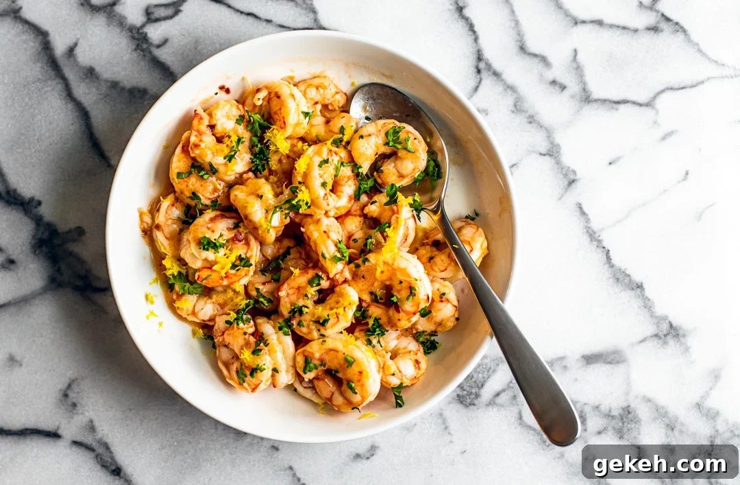 Spicy Lemon Garlic Shrimp with Chilies and Herbs 2 White serving bowl full of buttery shrimp garnished with fresh parsley.