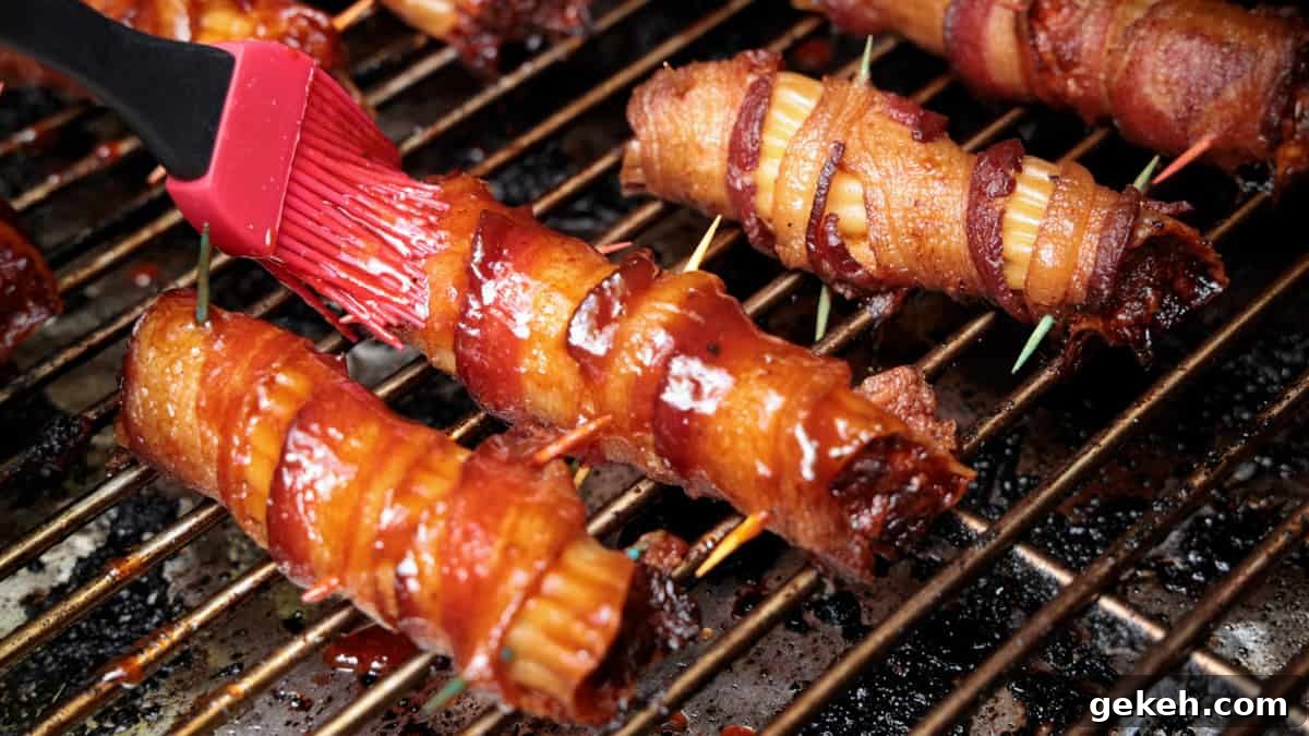 Brushing BBQ sauce on stuffed pasta shells while they are on a grill cooking.