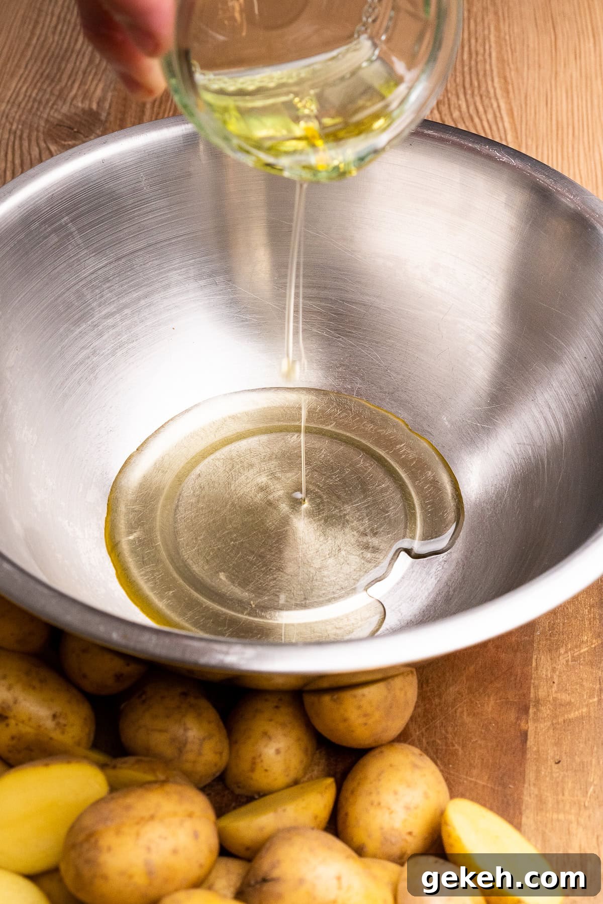 Crispy Air-Fried Baby Potatoes Recipe 13 Pouring olive oil into a large silver mixing bowl