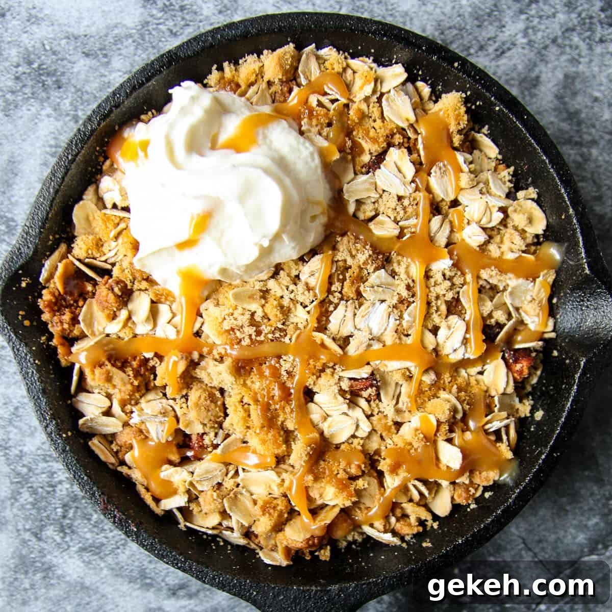 Air fryer apple crisp in a cast iron pan, drizzled with caramel sauce.