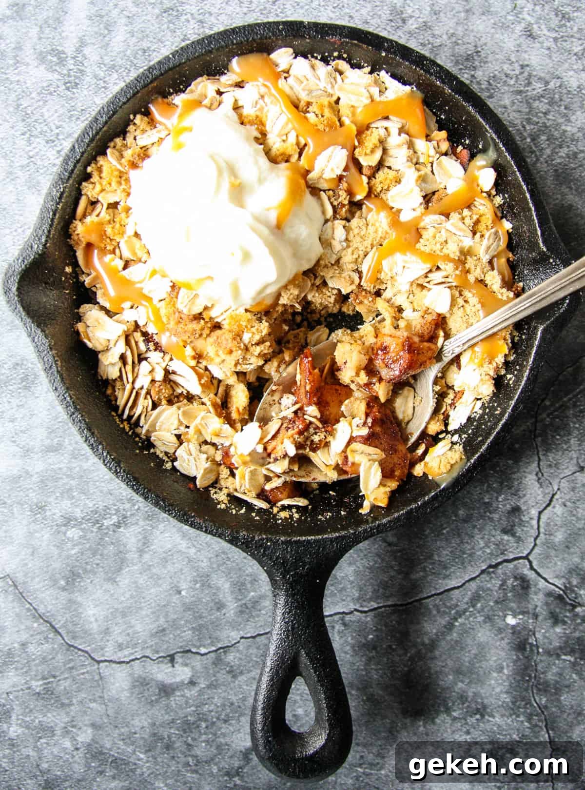 Apple crisp in a black pan with a silver spoon.