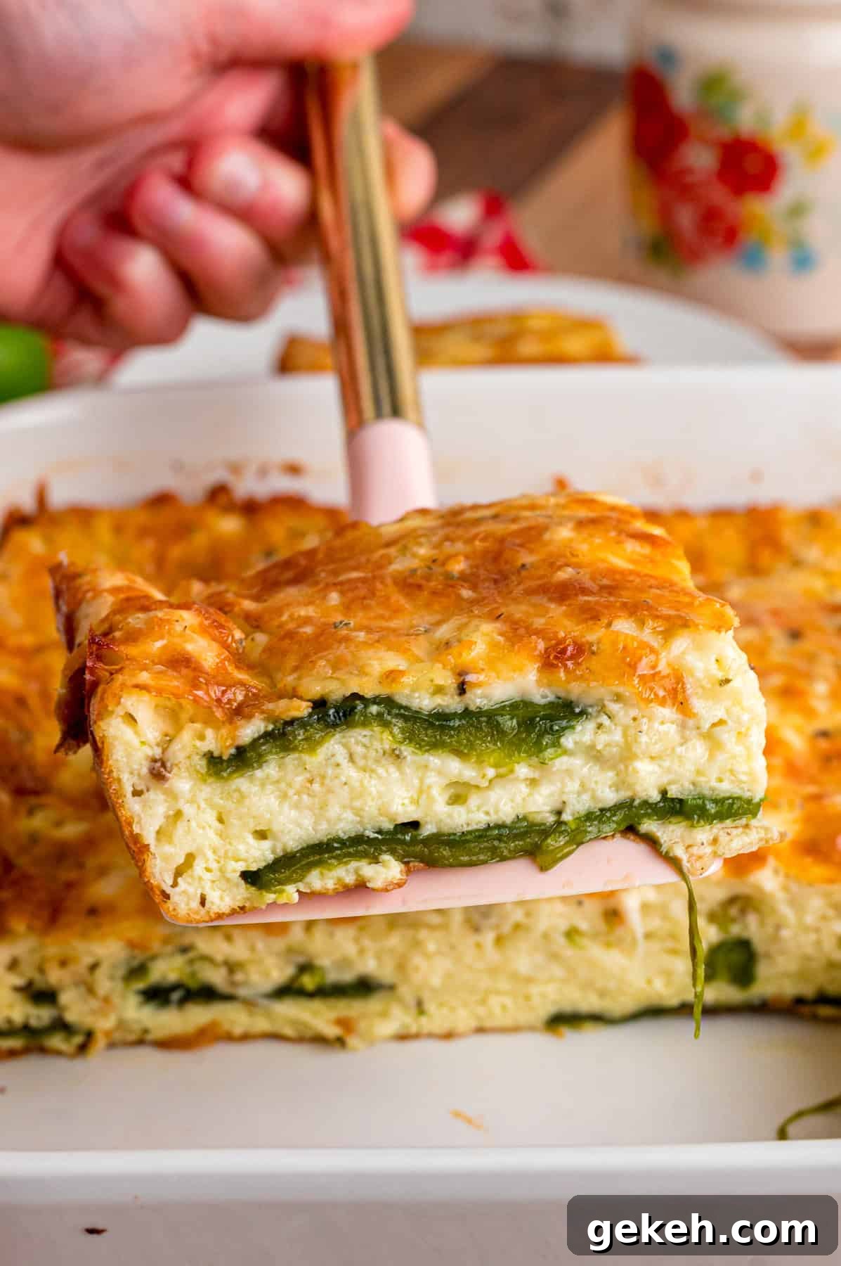 With layers of roasted poblano peppers and gooey cheese topped with fluffy eggs, this Chile Relleno Casserole is easy & flavorful. A slice of chile relleno casserole on a spatula