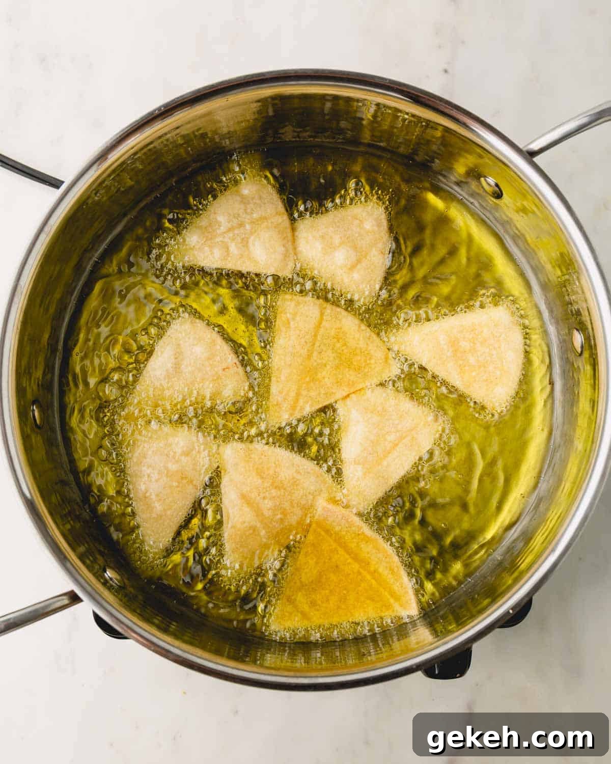Tortilla chips frying in a pot of oil.
