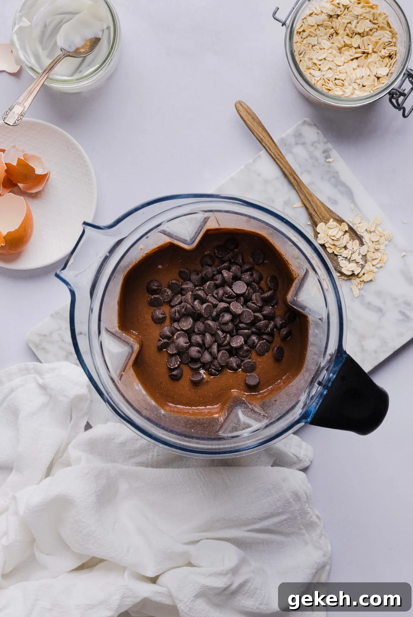 Ingredients for chocolate baked oats blended in a blender and chocolate chips stirred in.