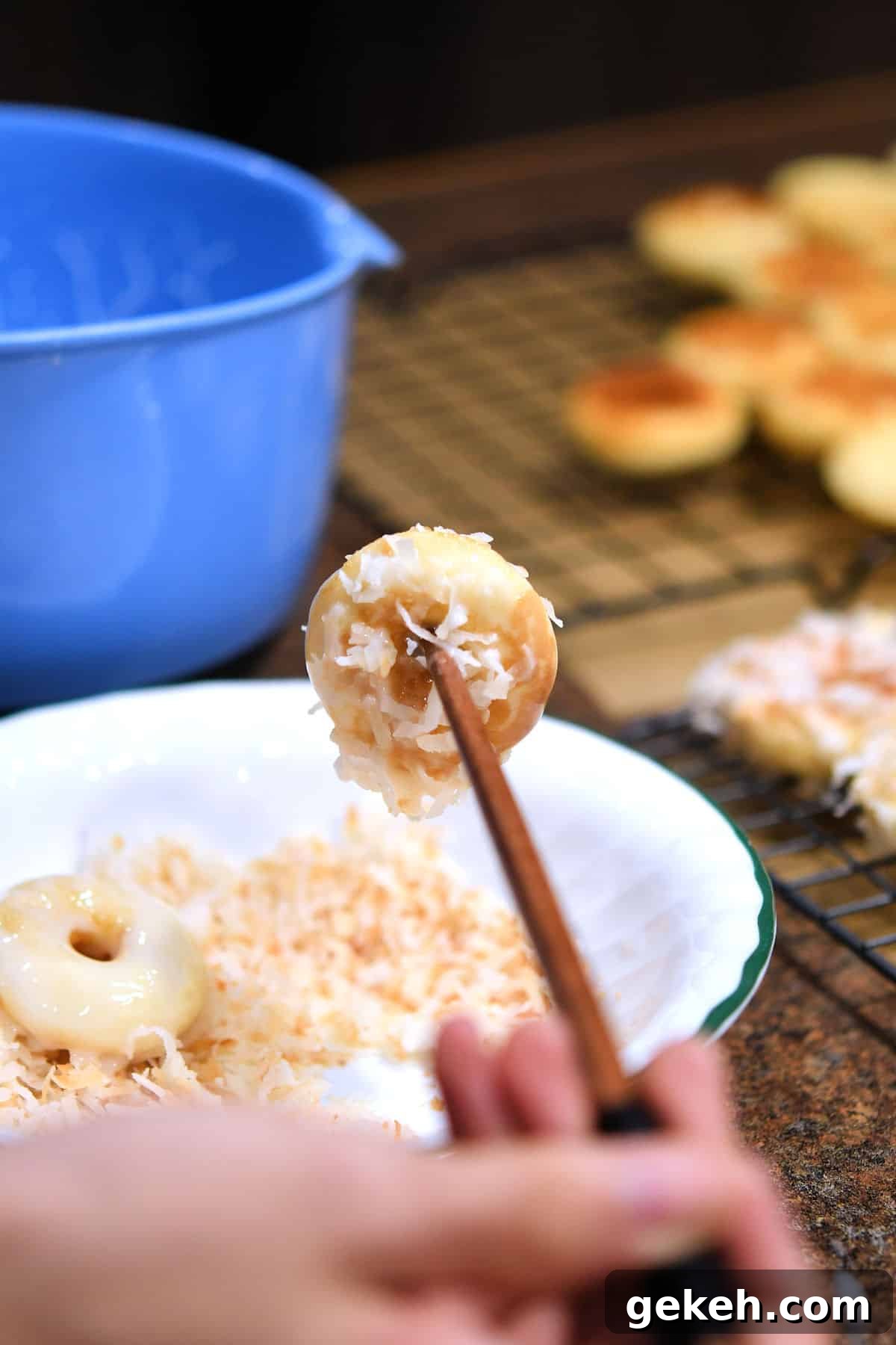 using chopsticks to dip mini donuts into glaze and toasted coconut.